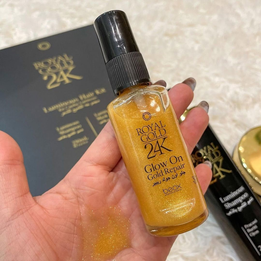 Hand holding a bottle of Royal Gold 24K Glow On Gold Repair product with a blurred background.