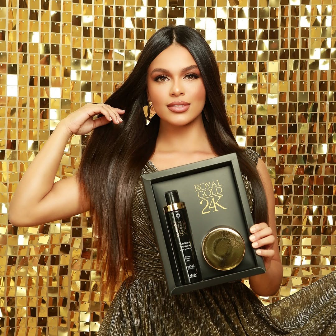 Woman holding a 'Royal Gold 24K' hair care product set against a gold mosaic background