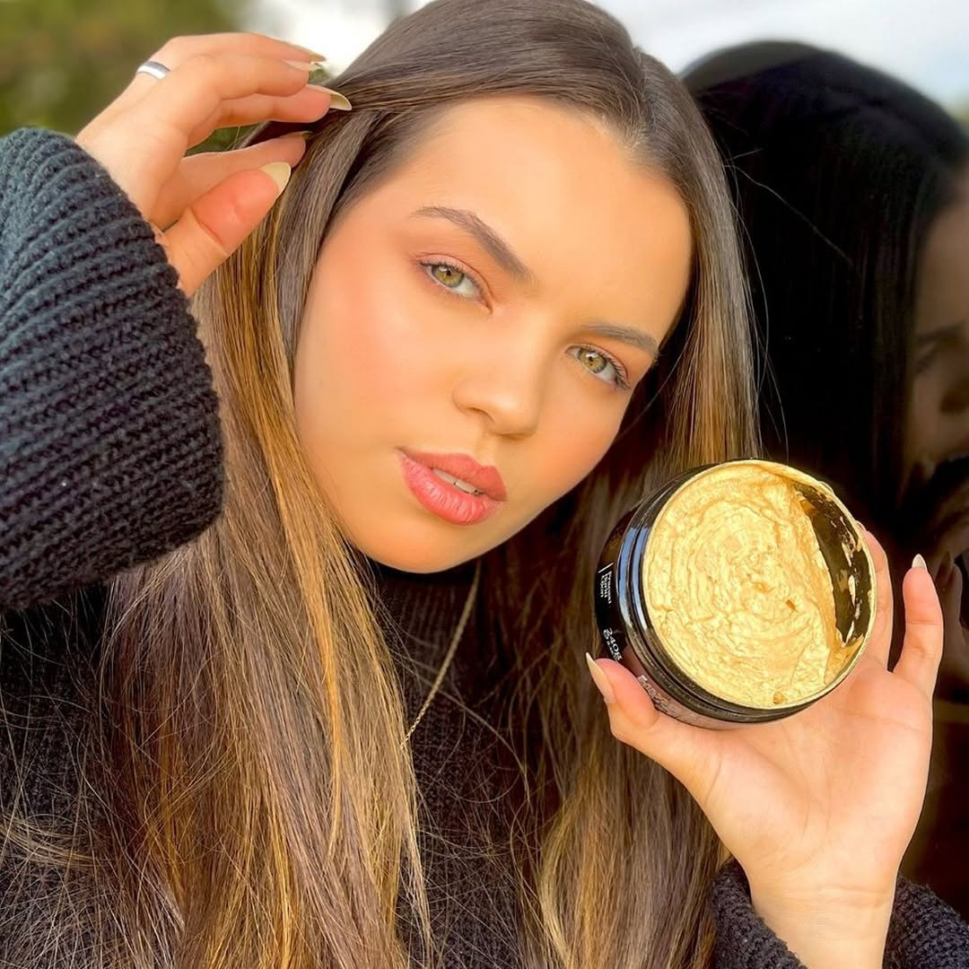 Woman holding a jar of hair product with another person in the background