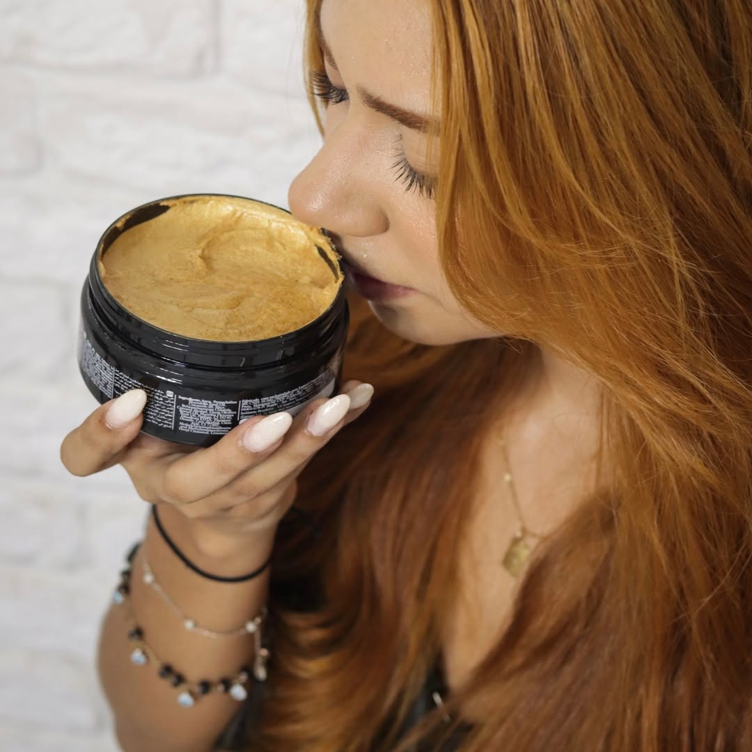 Woman with red hair holding a black container with a gold interior